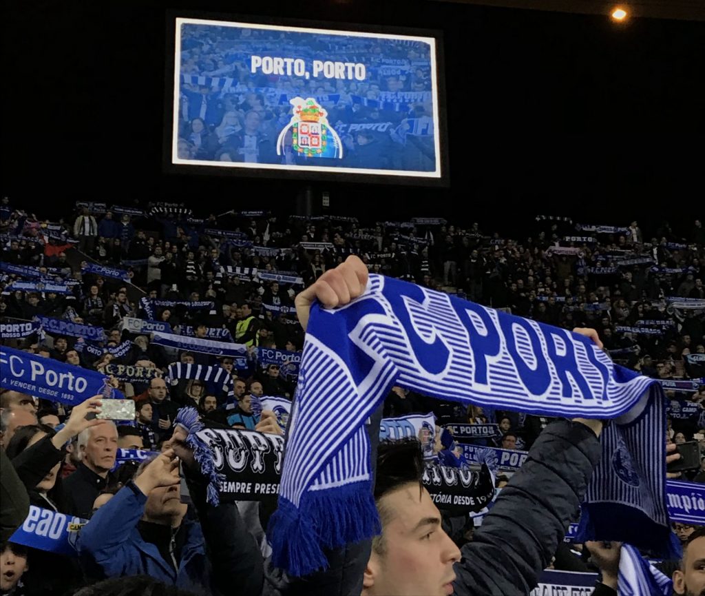 Man holds up a Porto team scarf while attending a soccer match at the Estadio Dragões.